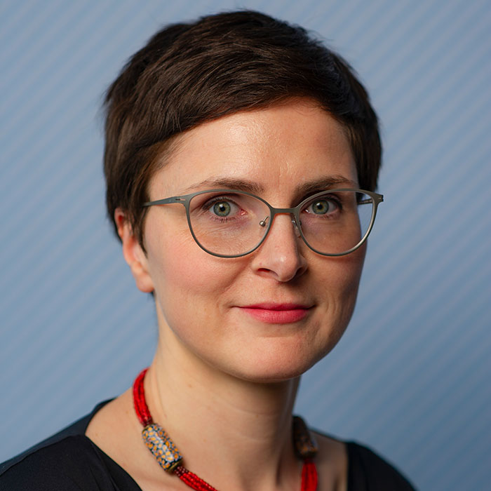 Portrait of Anna Nikolaeva against a pale blue background.